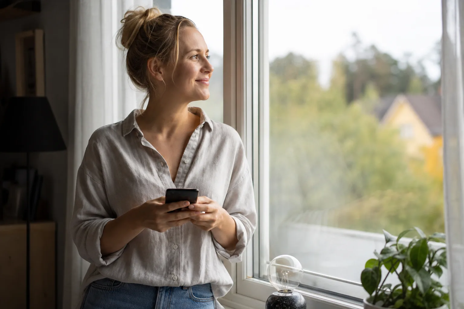 Ung person sitter ledigt i en soffa med en mobiltelefon i handen